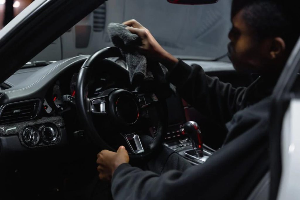 Interior detailing services provider cleaning a car’s steering wheel 