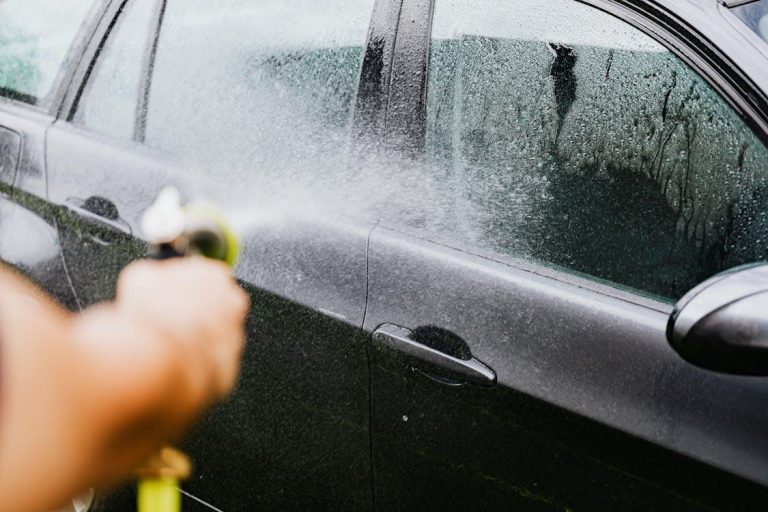 Mobile car detailing services provider washing a car using a pipe
