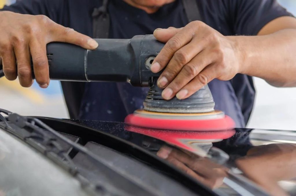 A professional car polishing expert buffing the front of a car
