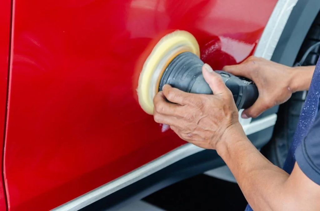 A professional car polishing expert buffing the side of a car