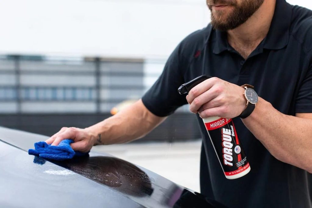 A professional odor removal expert spraying chemicals on a car and wiping it using a cloth