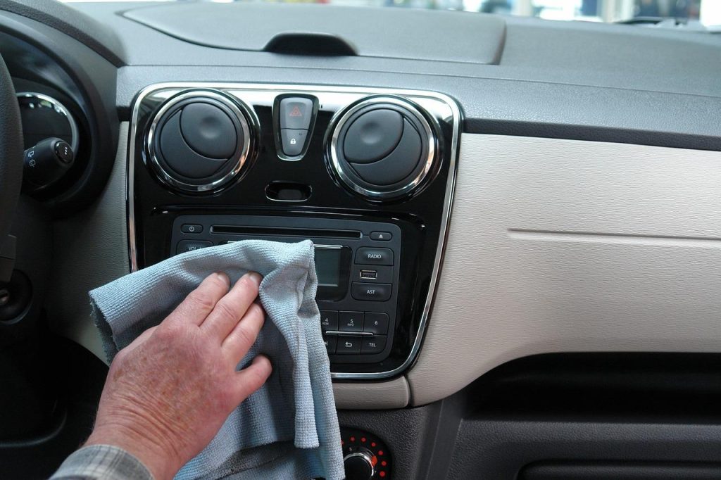A car odor removal expert cleaning the dashboard using a cloth