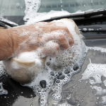 A car detailing professional cleaning a car with a sponge
